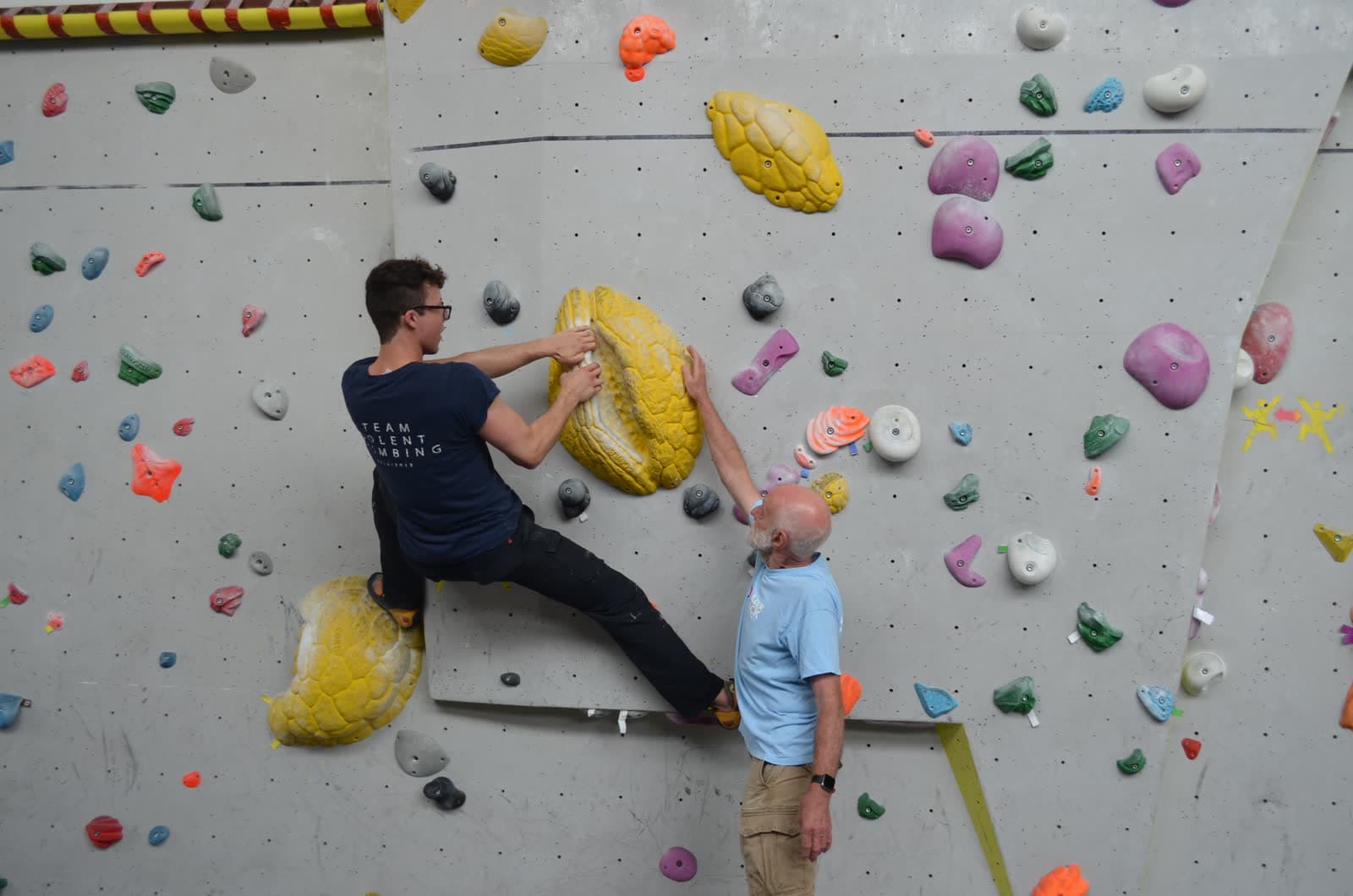 A coach pointing out the next hold to a climber