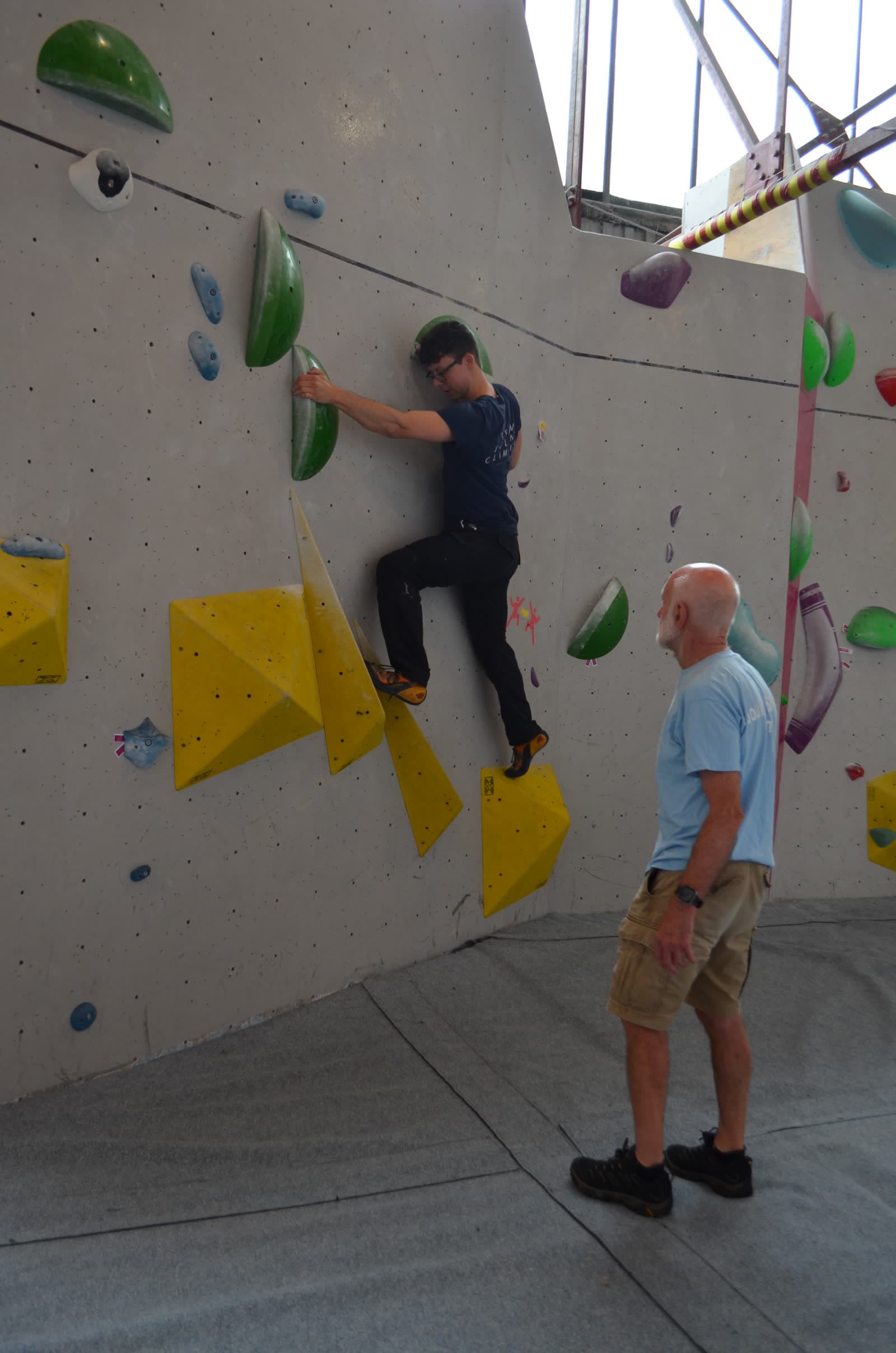 A climber on a steep section with a coach spotting her