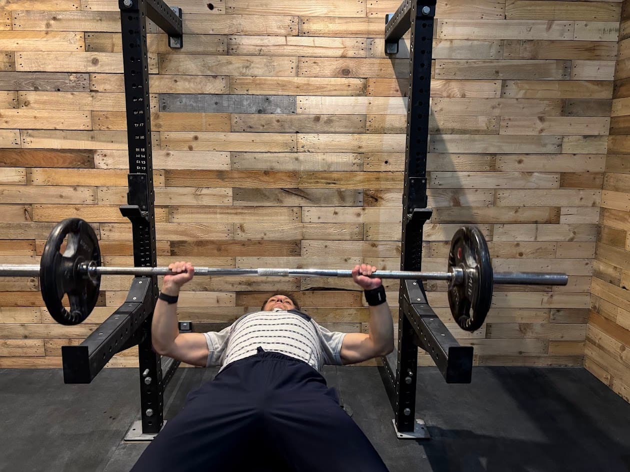 Someone bench pressing a barbell in the rack