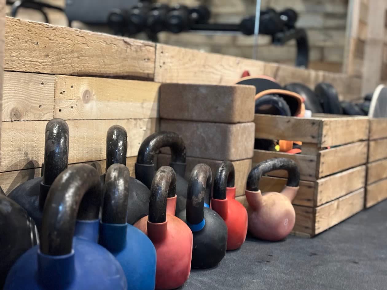 A row of kettlebells lined up in front of the pallet wall