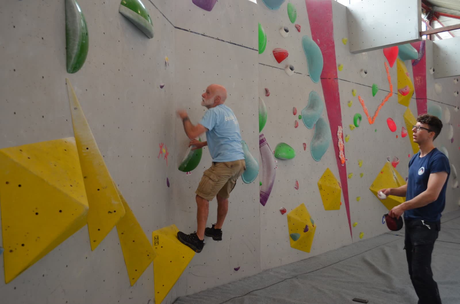 An older climber moving steadily across the wall