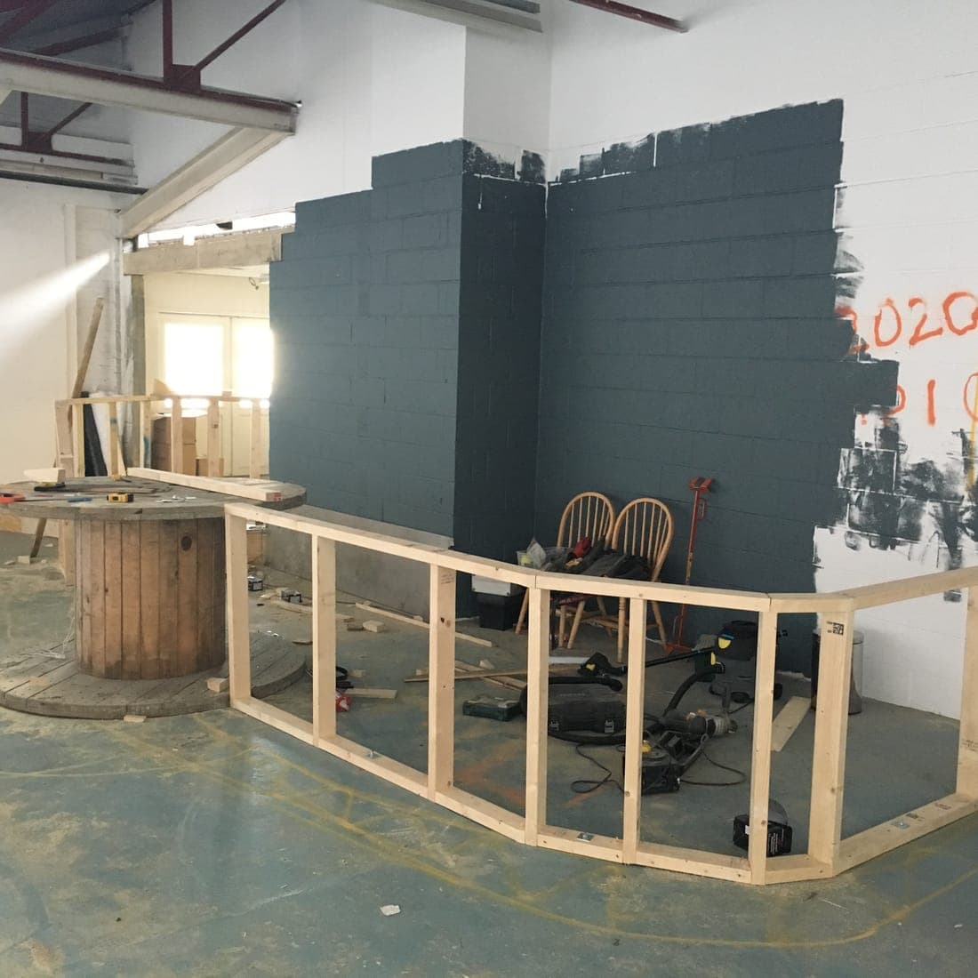 The timber frame of the reception desk going up in front of a half painted wall
