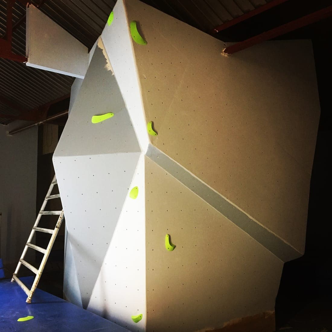 A newly built wall panel with its first few holds on, a ladder beside it