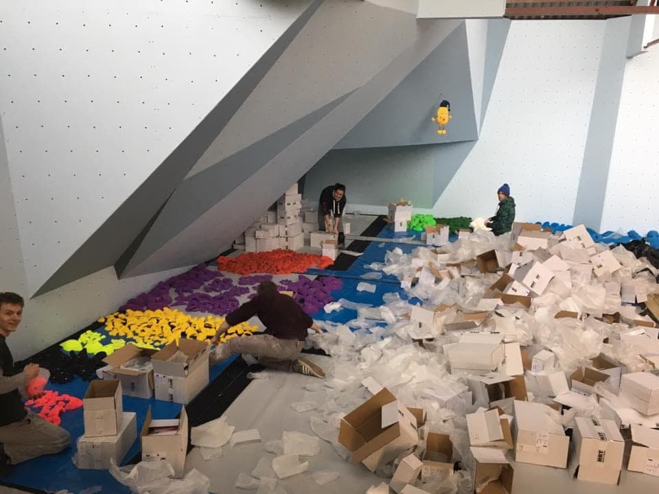 Boxes of new climbing holds being unpacked and sorted on the mats