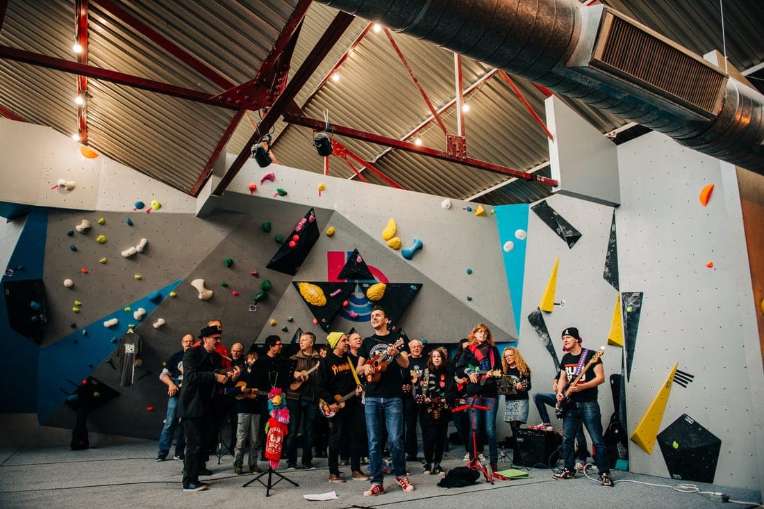 A ukulele band playing on the mats under the wall