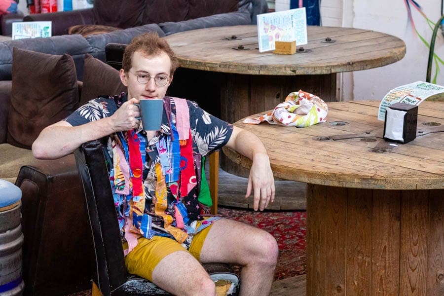 A climber in a loud shirt drinking tea on the café sofa