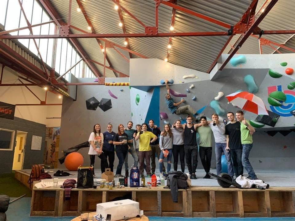A line of climbers arm in arm on the mats at a Christmas social, one of them still on the wall behind
