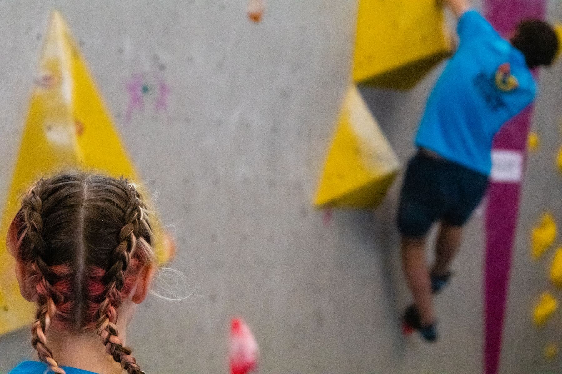 A girl with plaits watching a friend climb