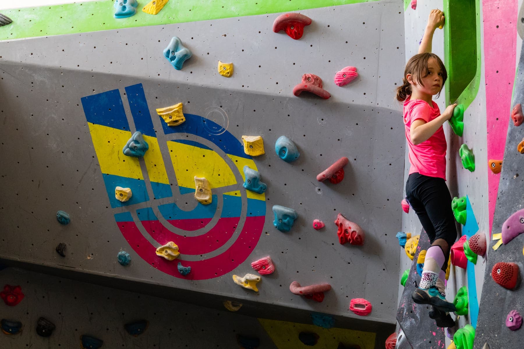 A young climber on the wall beside the Boulder Shack logo