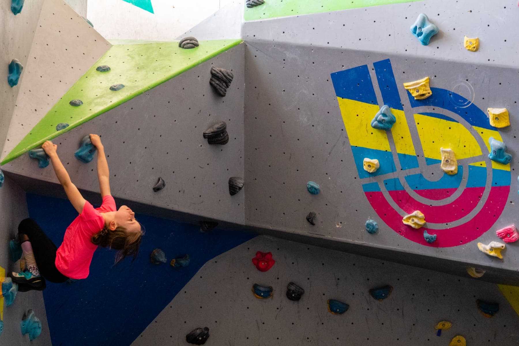A girl in a pink top climbing a steep section of wall
