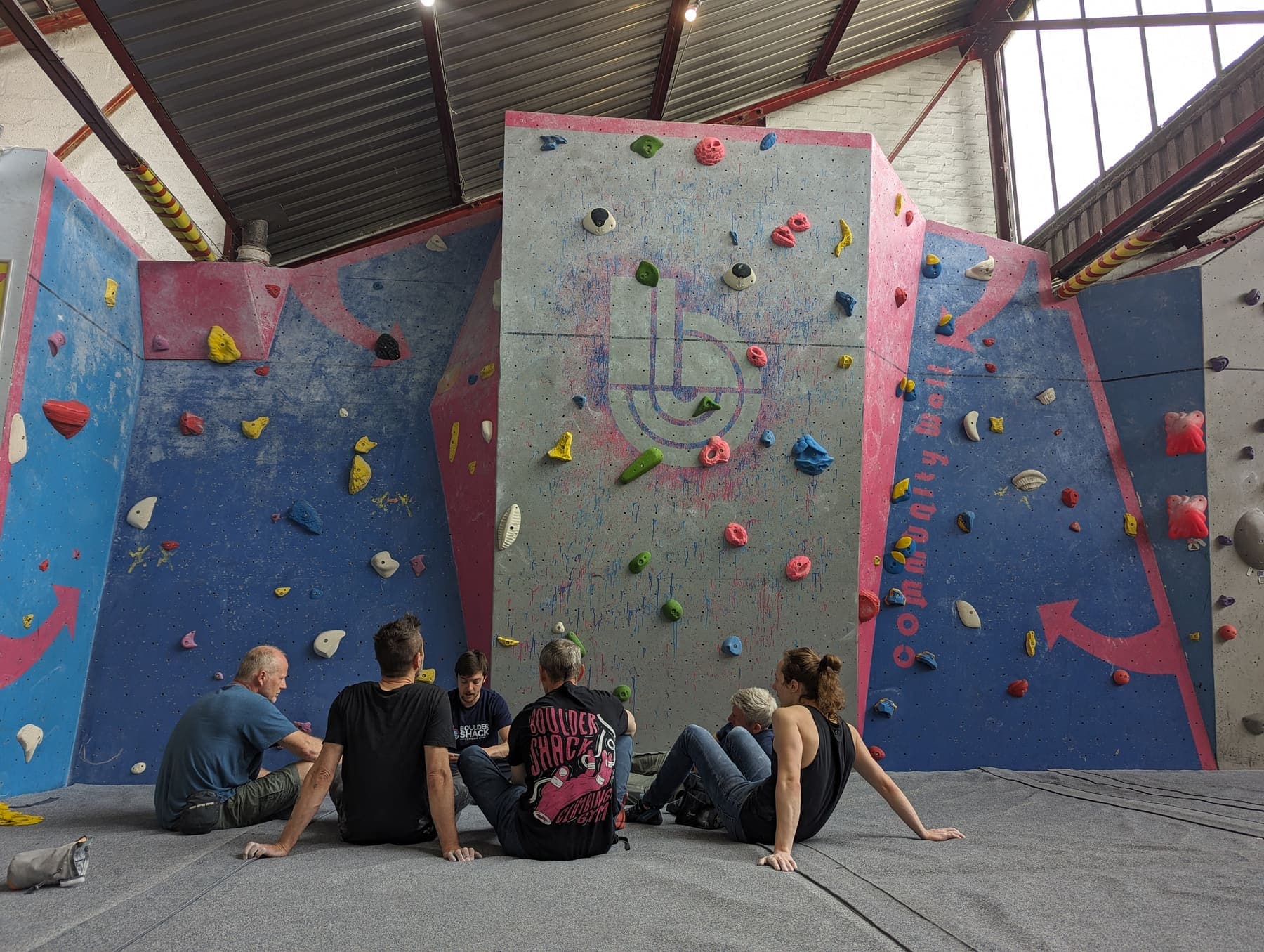 A group of climbers sitting on the mats under the wall, chatting