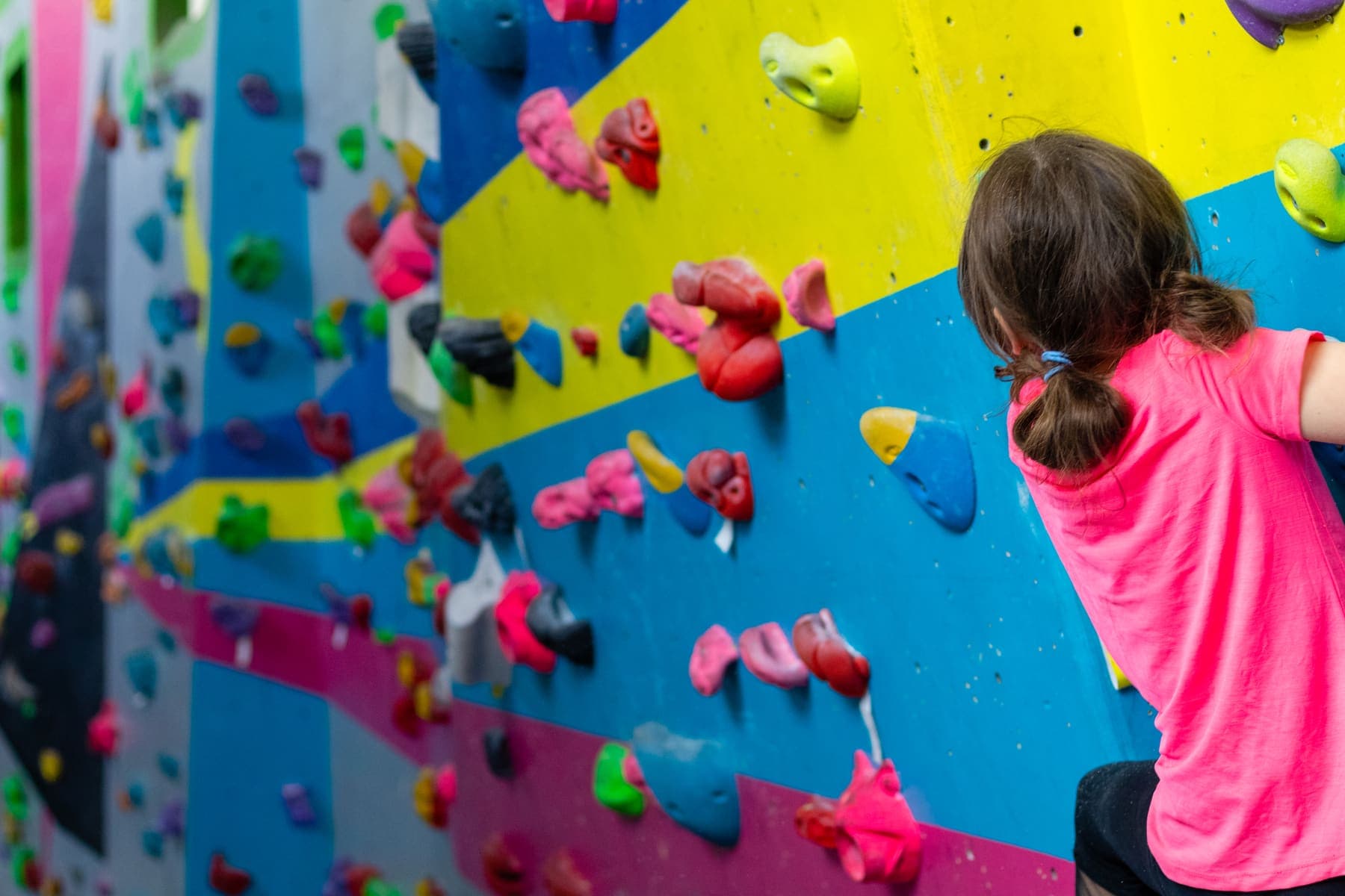 A girl in a pink top on the yellow and blue wall