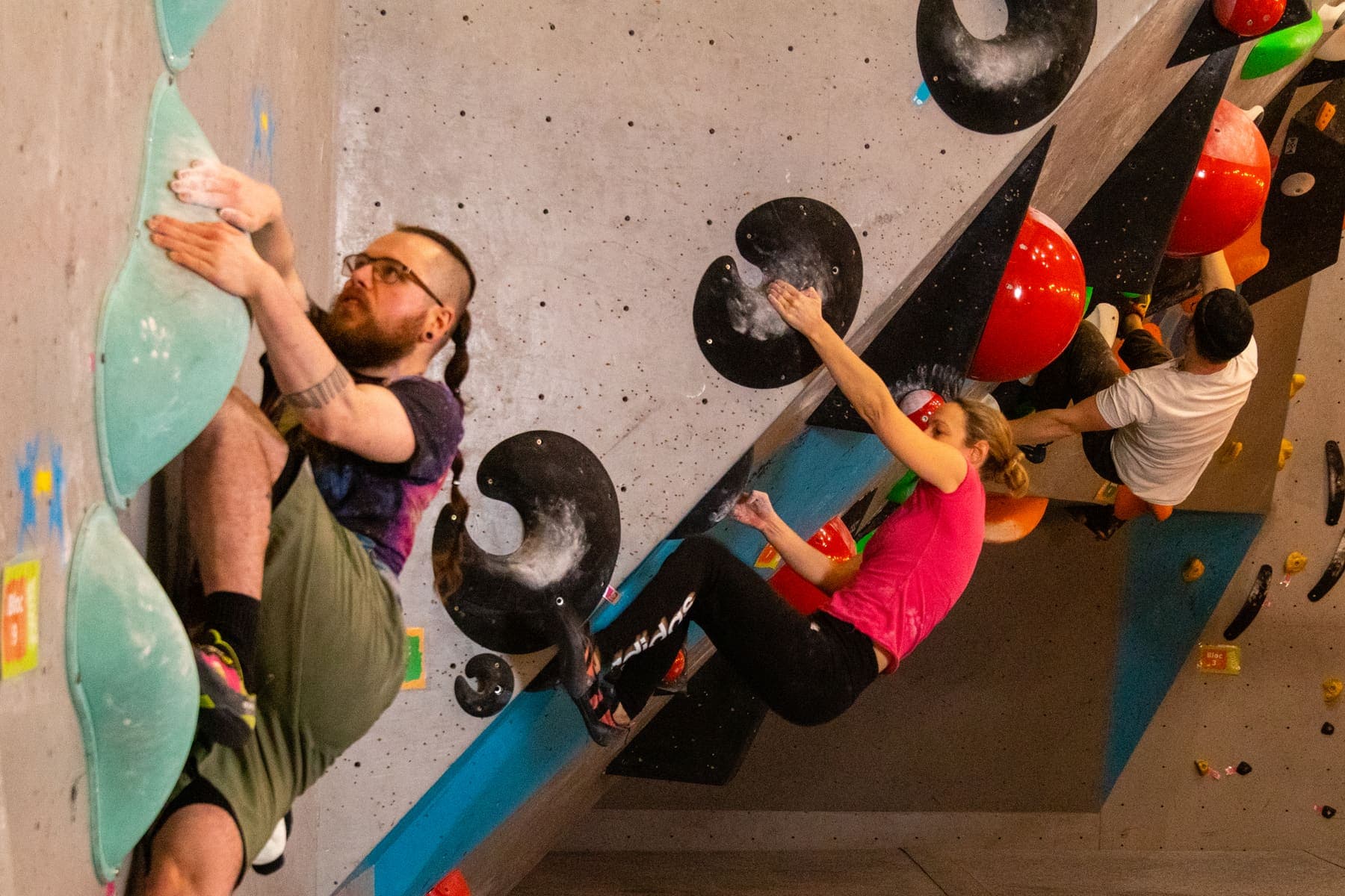 Two new climbers on the wall, one grinning down at the camera