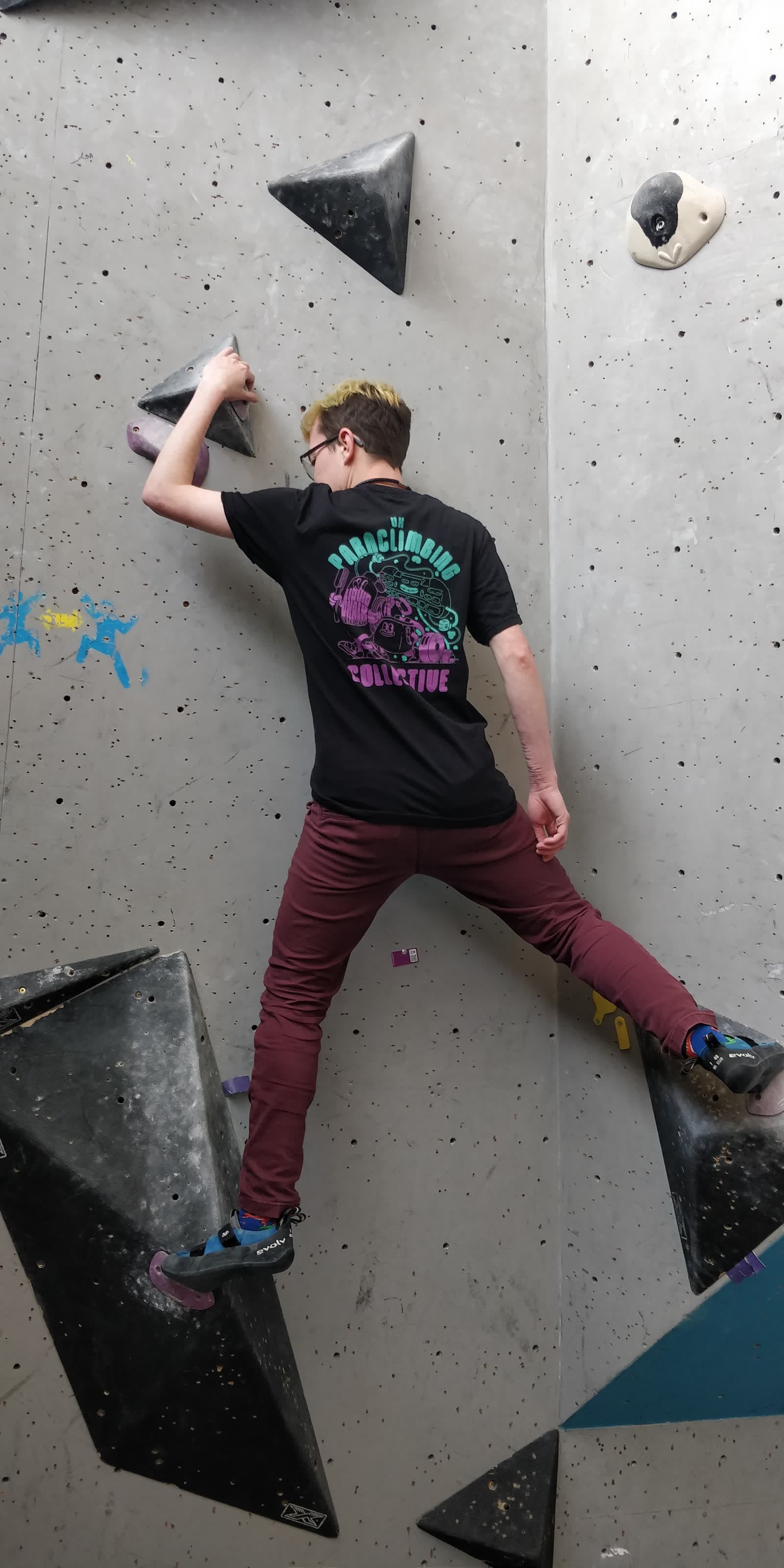 A climber in a Paraclimbing Collective shirt working a problem