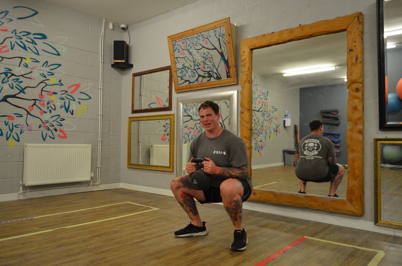 A coach in a deep squat holding a kettlebell in the studio