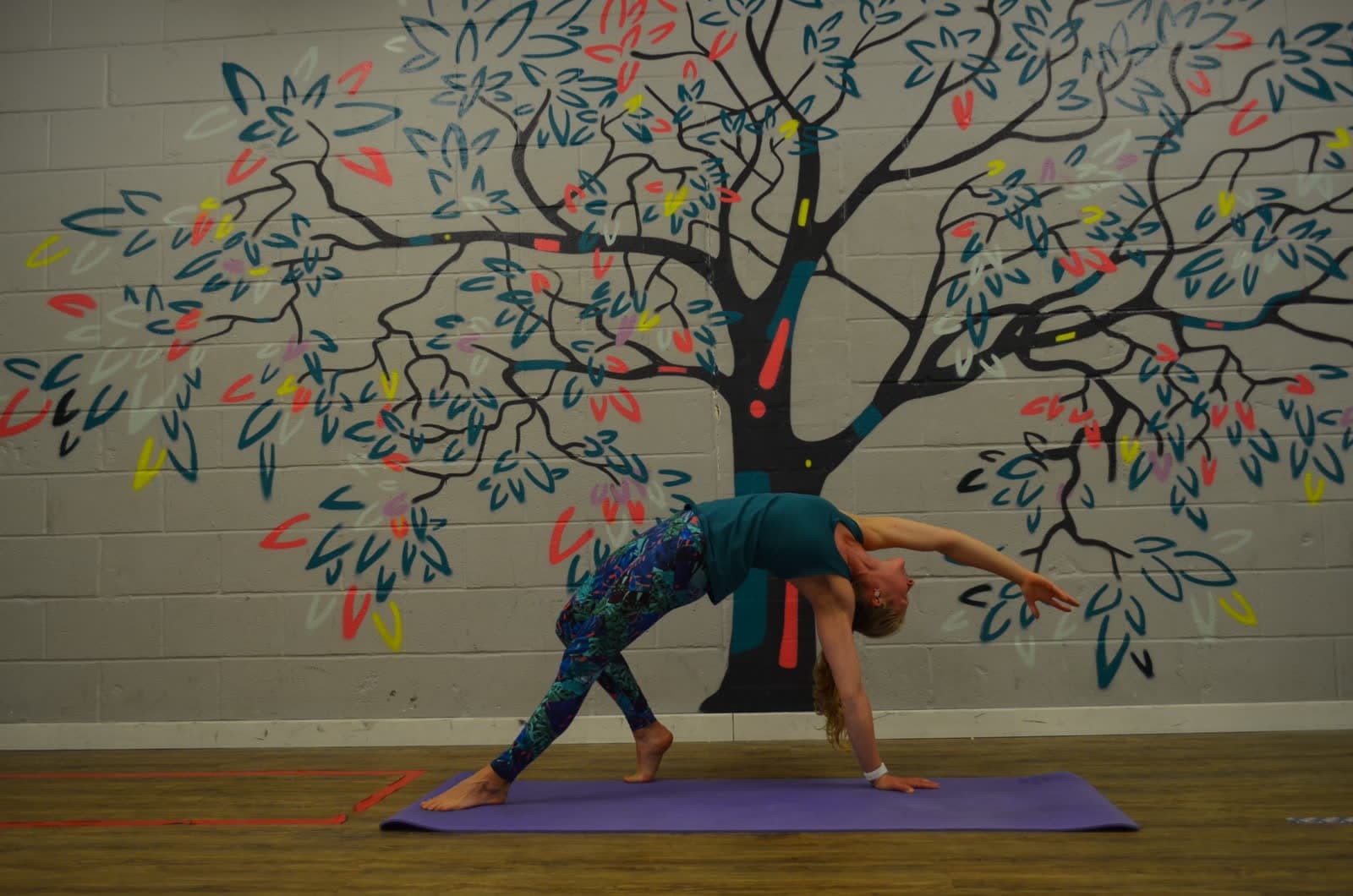 A yoga pose in the studio, mirror and mural behind